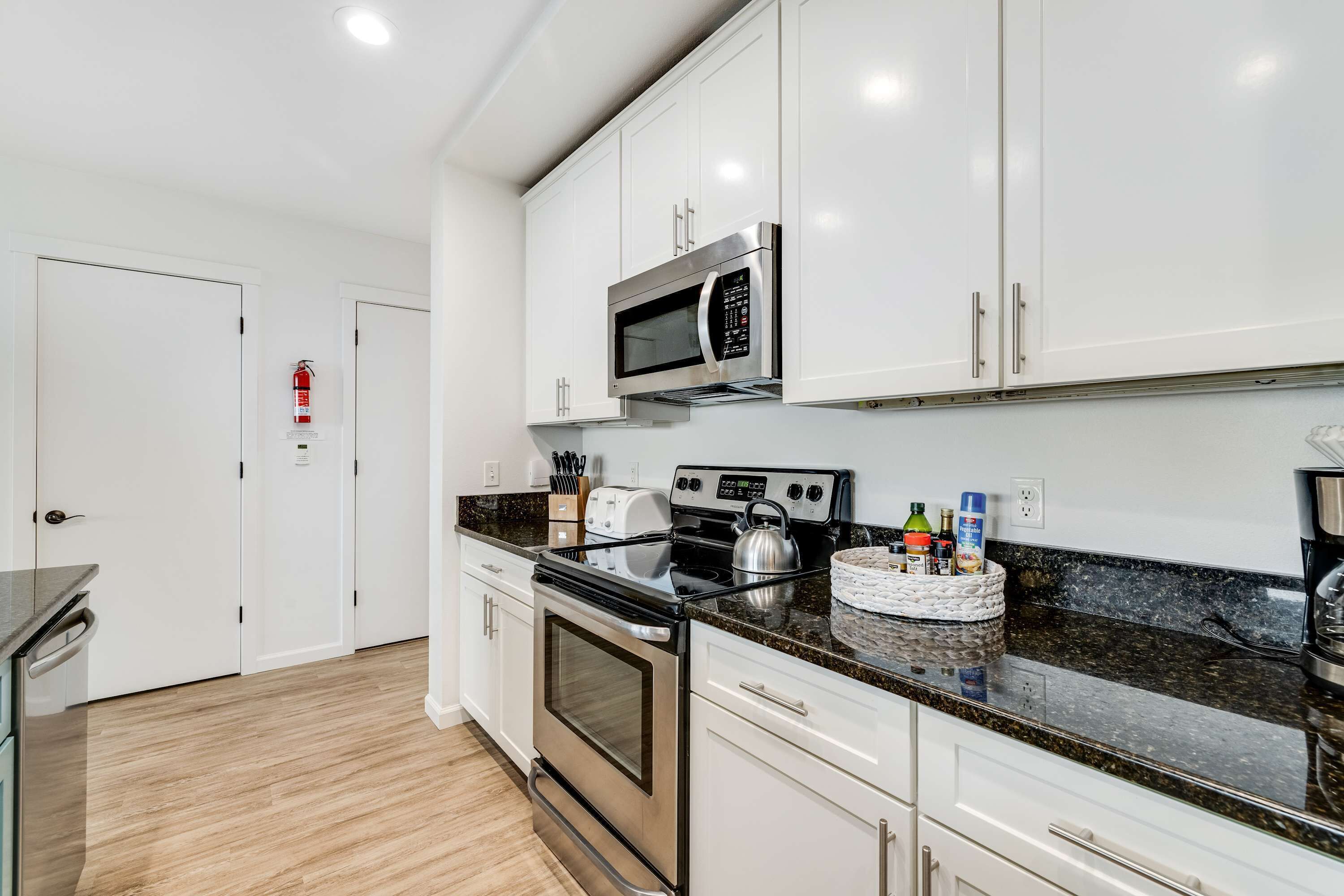 A modern kitchen with white cabinets, stainless steel appliances, and a granite countertop.