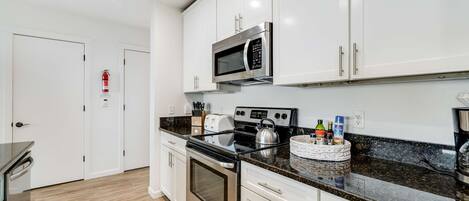 A modern kitchen with white cabinets, stainless steel appliances, and a granite countertop.