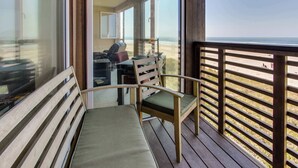 Un balcone con una panchina in legno e una sedia, con vista sulla spiaggia.