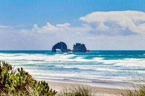 A beach with two rock formations in the ocean. - Modern Waterfront Condo Right on the Pacific Ocean Dogs Welcome (Rockaway Beach)