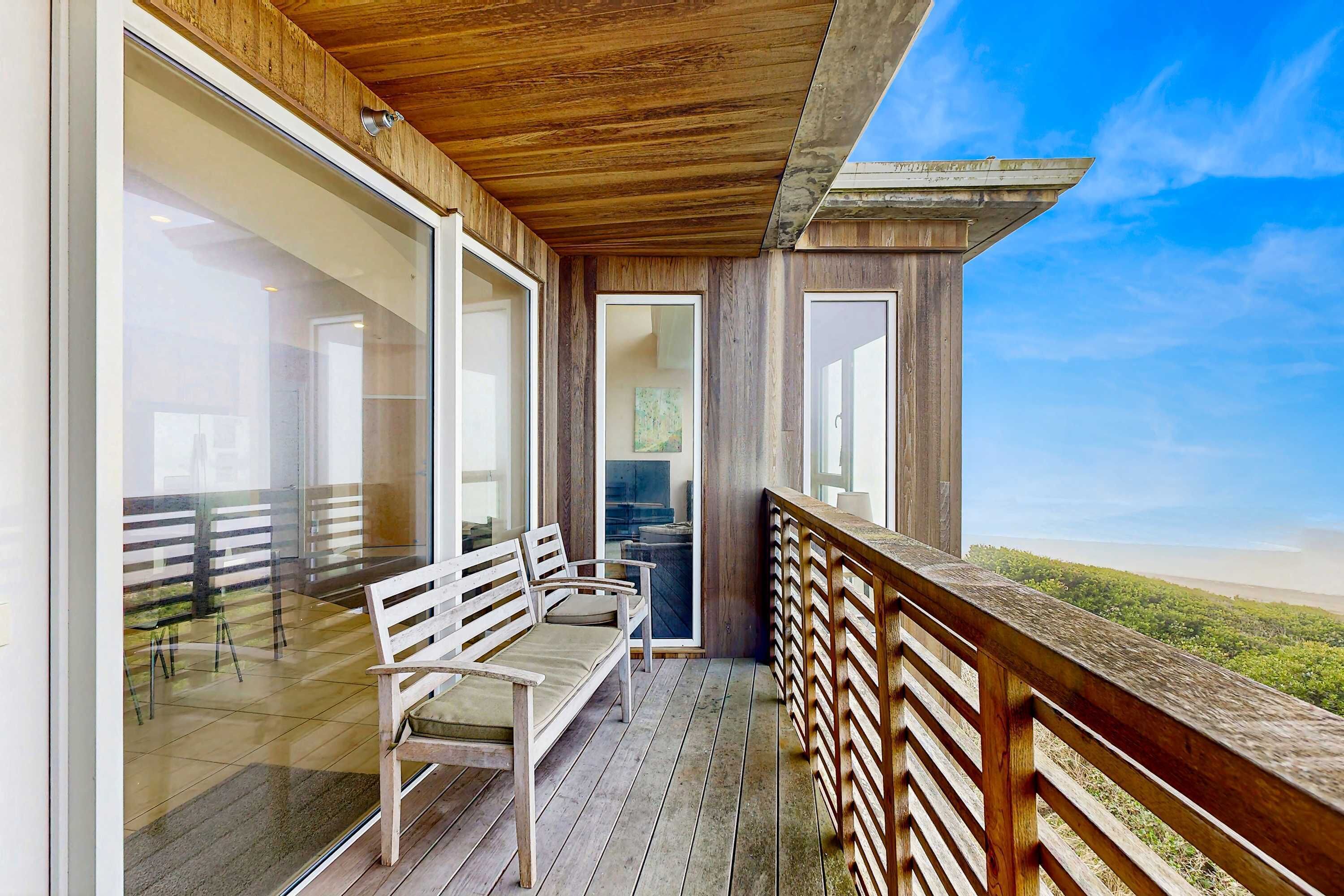 Une terrasse en bois avec un banc et une rambarde donnant sur une plage.
