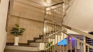 Un escalier avec une rampe, une plante en pot et un comptoir d’accueil.