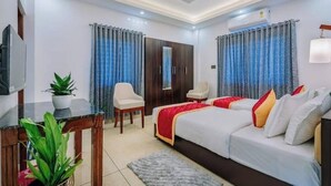 Une chambre d’hôtel avec un lit, un bureau, une chaise, une télévision et des rideaux.