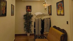 Un couloir avec un plancher en bois, un canapé, un lit avec des oreillers et une plante en pot.