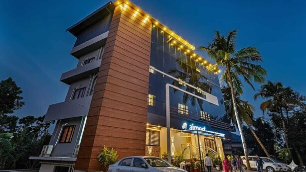 Un hôtel moderne, reconnaissable à son grand panneau « Air Motel », qui se distingue par son architecture à plusieurs étages, avec une façade combinant verre et bois, et une entrée bien éclairée.