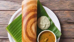 Une assiette contenant un dosa, une sauce à la noix de coco et un sambar.