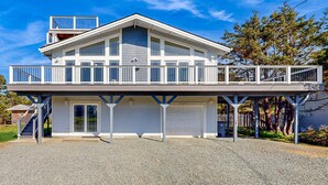 A two-story house with a balcony, a garage, and a covered driveway. - Ocean side home steps from sand dog friendly (Rockaway Beach)