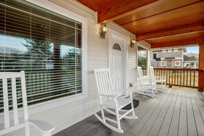 A wooden deck with white rocking chairs and a door with a window. - Comfortable home with a private game room blocks from the beach (Rockaway Beach)