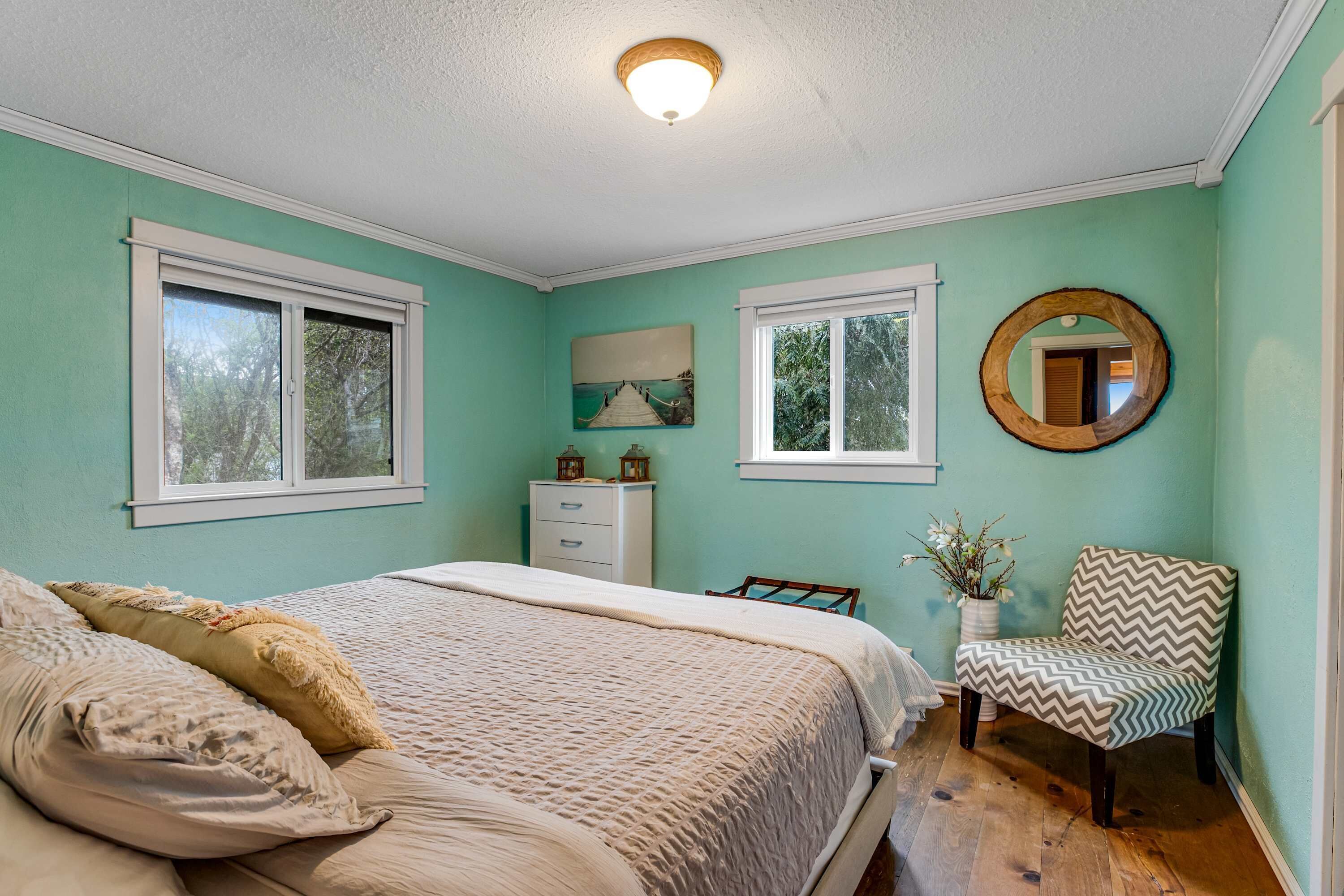 A bedroom with a bed, a chair, a dresser, and a window.