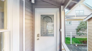 Una puerta blanca con un panel de vidrio decorativo y un ventanal pequeño.