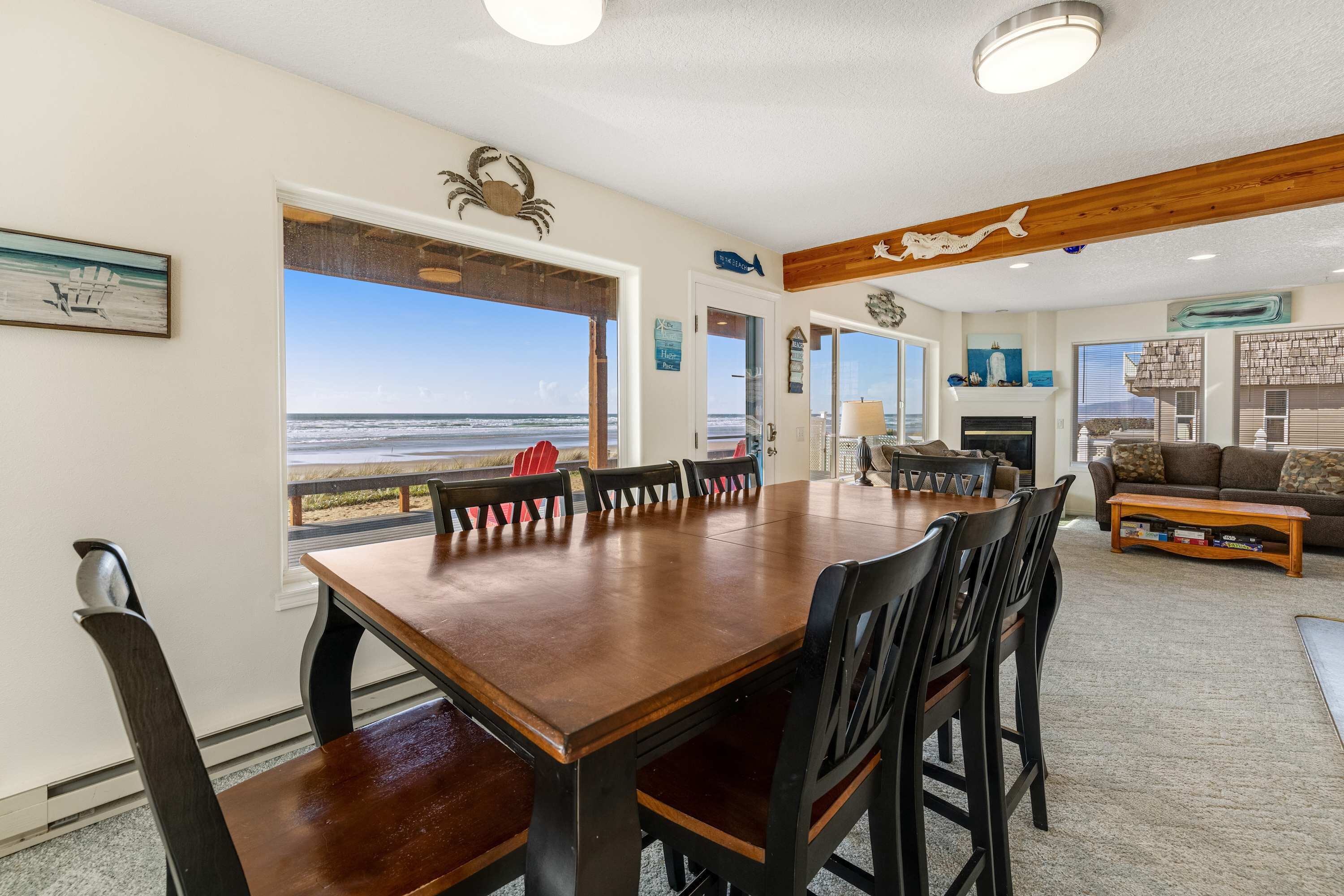 Un salon spacieux avec une grande table à manger en bois, des sièges confortables et une vue sur la plage.