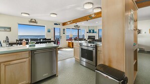 Een keuken met uitzicht op zee, roestvrijstalen apparatuur en houten details.