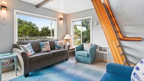 A modern living room with a grey sofa, blue armchair, and a blue carpet. - Dog friendly home across street from beach with rooftop deck and views (Rockaway Beach)
