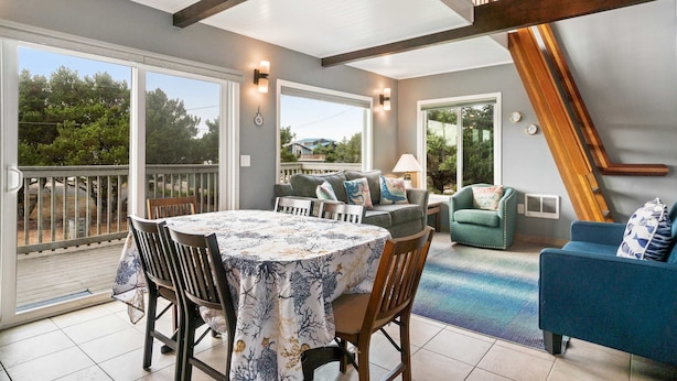 A spacious patio with a dining table, chairs, and a blue sofa. - Dog friendly home across street from beach with rooftop deck and views (Rockaway Beach)