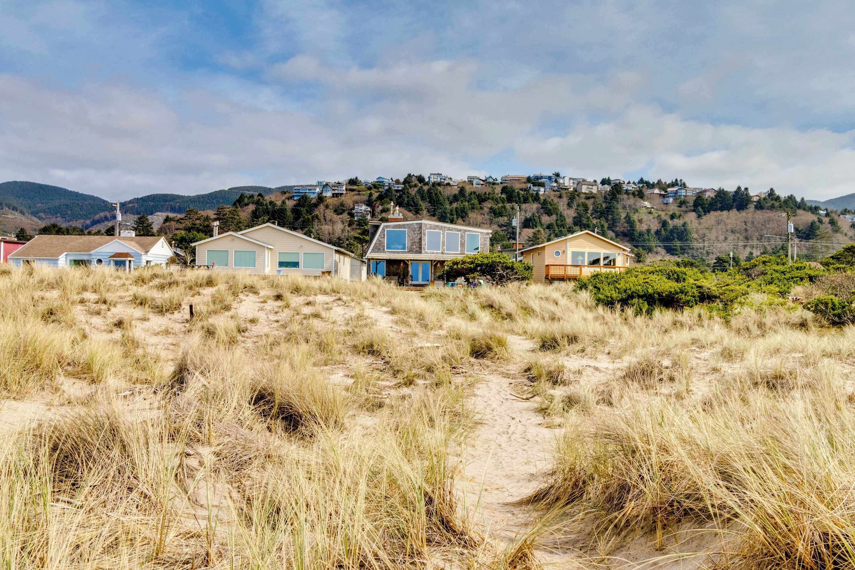 Une propriété située sur la côte, comprenant plusieurs maisons construites sur une colline, et entourée de dunes herbeuses.