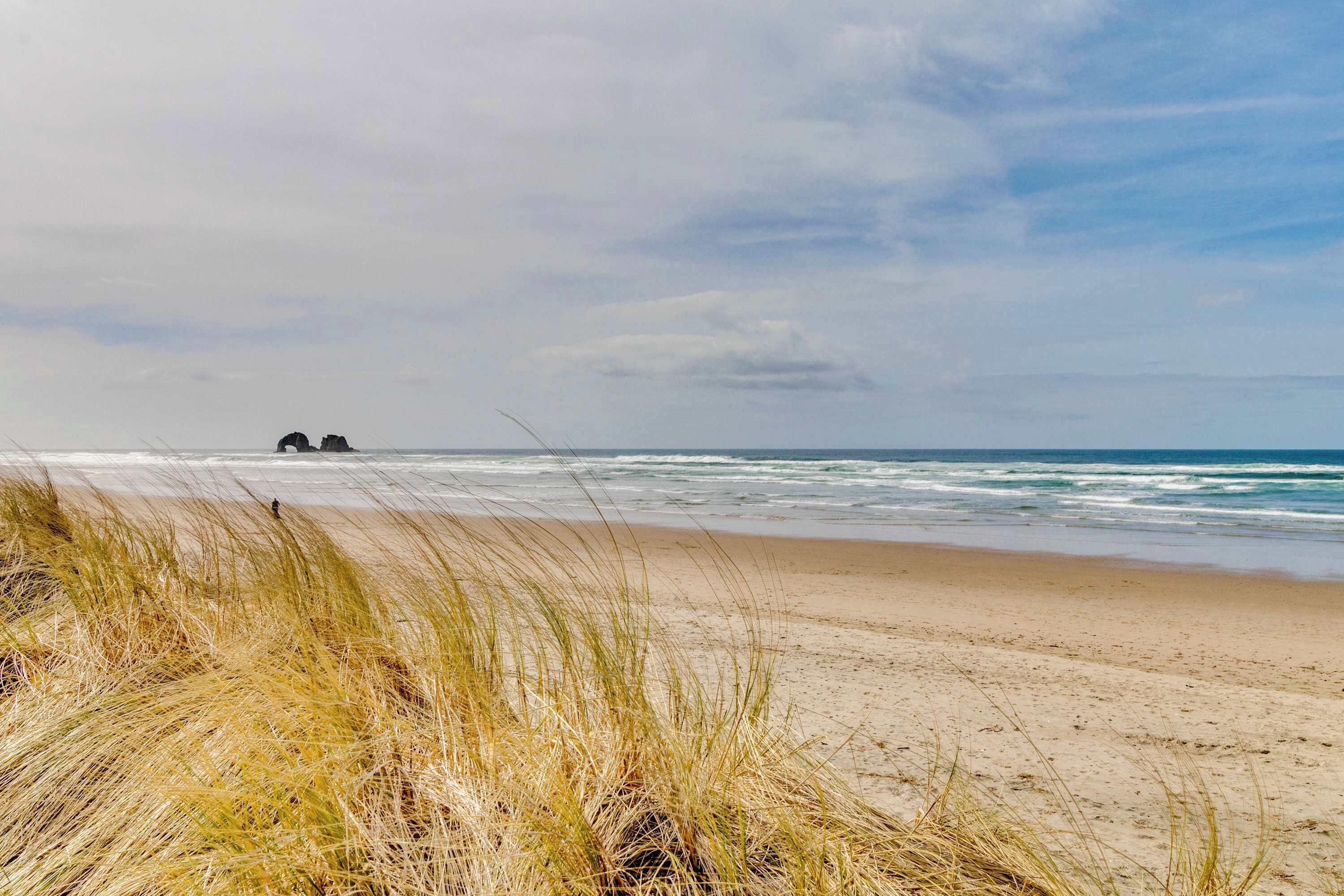 Une plage avec des dunes de sable et une vue dégagée sur l’océan.