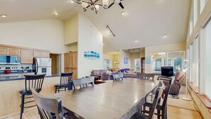 Een ruime keuken met moderne apparatuur, een eetgedeelte met houten stoelen, en een woonkamer met een bank en televisie.