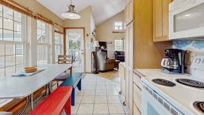 Una cocina con comedor, estufa y cafetera.