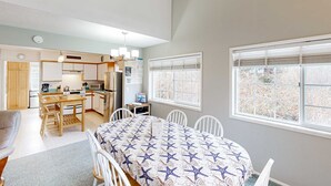 A compact, well-lit room with a kitchenette, a dining area, and large windows providing natural light. - Cozy family home away from home dog friendly with nearby beach access and hot tub (Rockaway Beach)