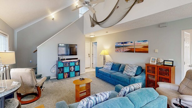 A cozy living room with a blue sofa, a wooden coffee table, and a ceiling fan. - Cozy family home away from home dog friendly with nearby beach access and hot tub (Rockaway Beach)