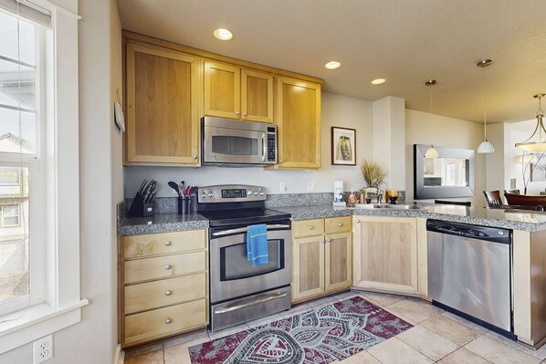 A modern kitchen with wooden cabinets, stainless steel appliances, and a granite countertop. - Dog friendly beach condo in a great location for exploring Rockaway Beach (Rockaway Beach)