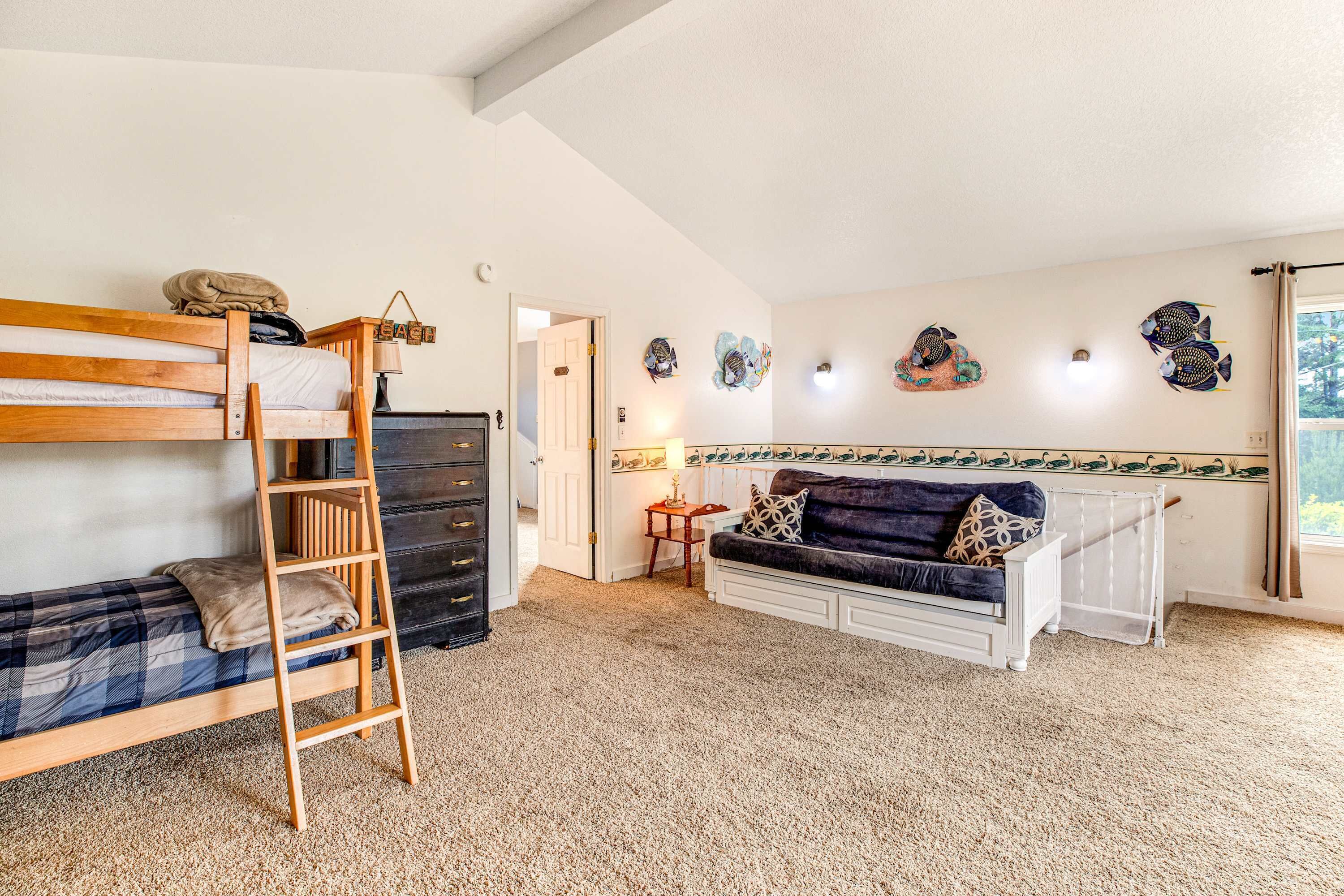 Ein Zimmer mit einem Etagenbett, einer Schlafcouch, einer Stehleiter, einem kleinen Tisch und Wanddekoration.