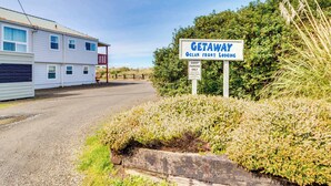 Schild für 'GETAWAY Ocean Front Lodging' mit einem Schild für Gästezufahrt und einem Schild mit der Aufschrift 'Abschleppen'.
