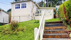 Une maison à deux étages avec un porche à l’avant et un escalier menant à l’entrée.