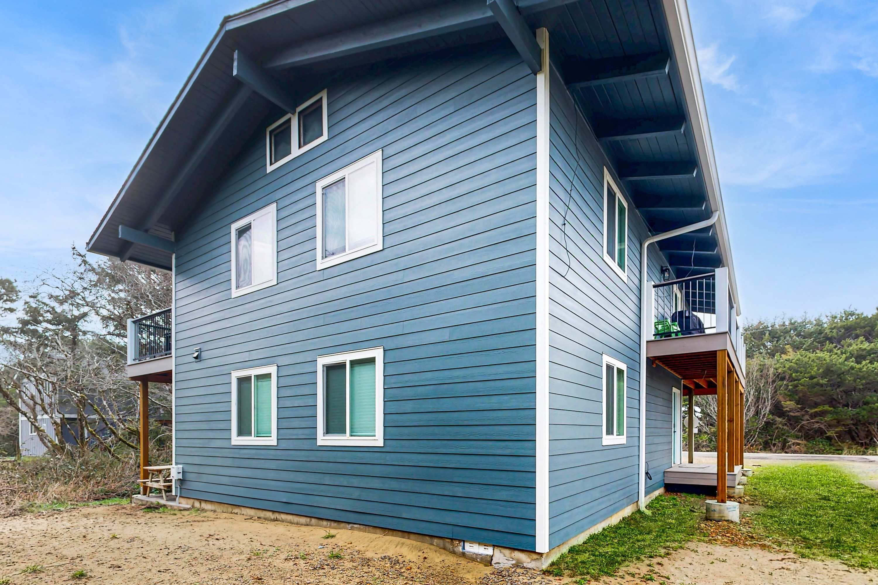 Une maison à deux étages avec un porche couvert et une petite terrasse.