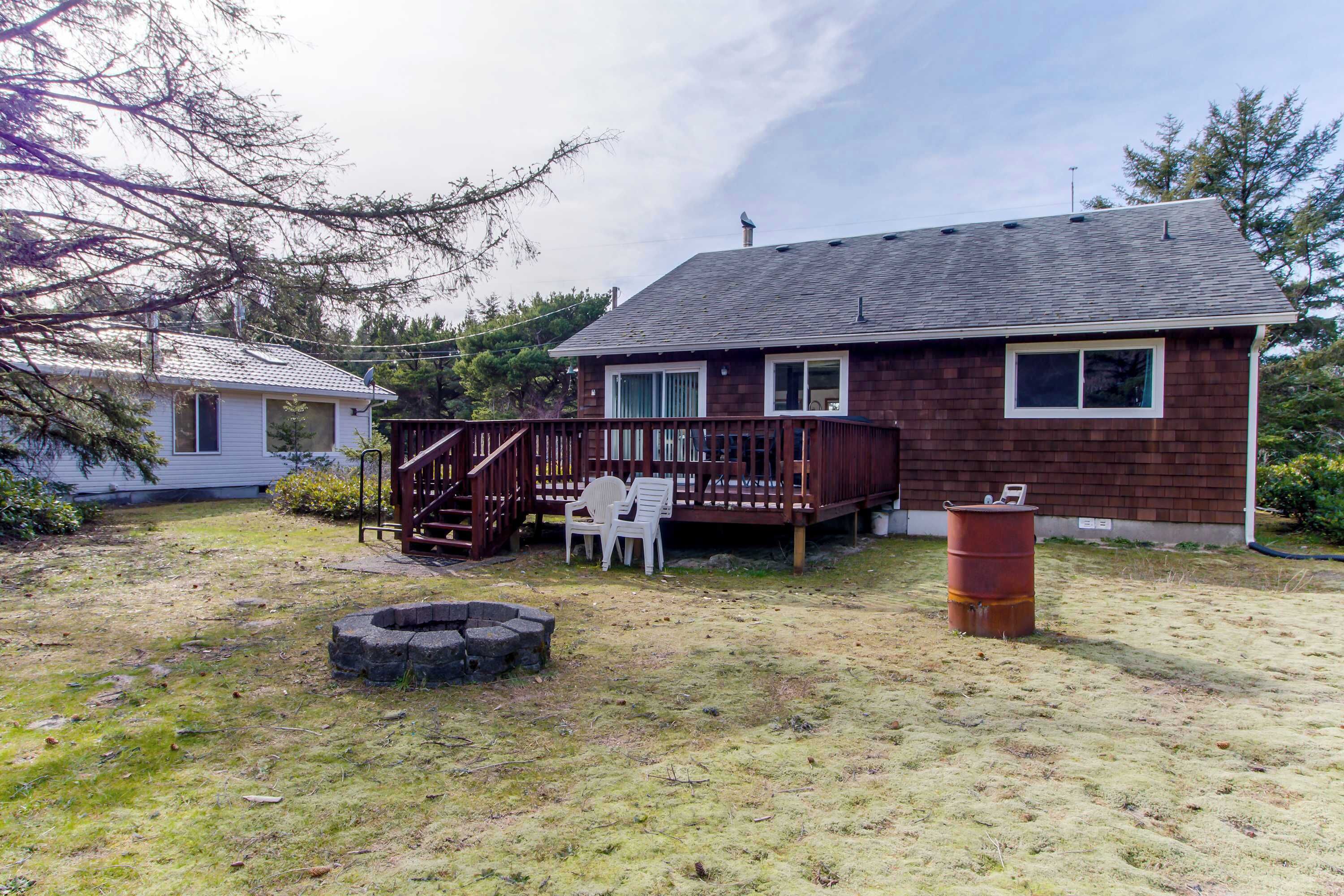 Une maison à deux étages avec une terrasse en bois, un foyer et un tonneau.