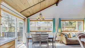 Un salón acogedor con techo de madera, una zona de comedor con mesa y sillas, y un sofá.