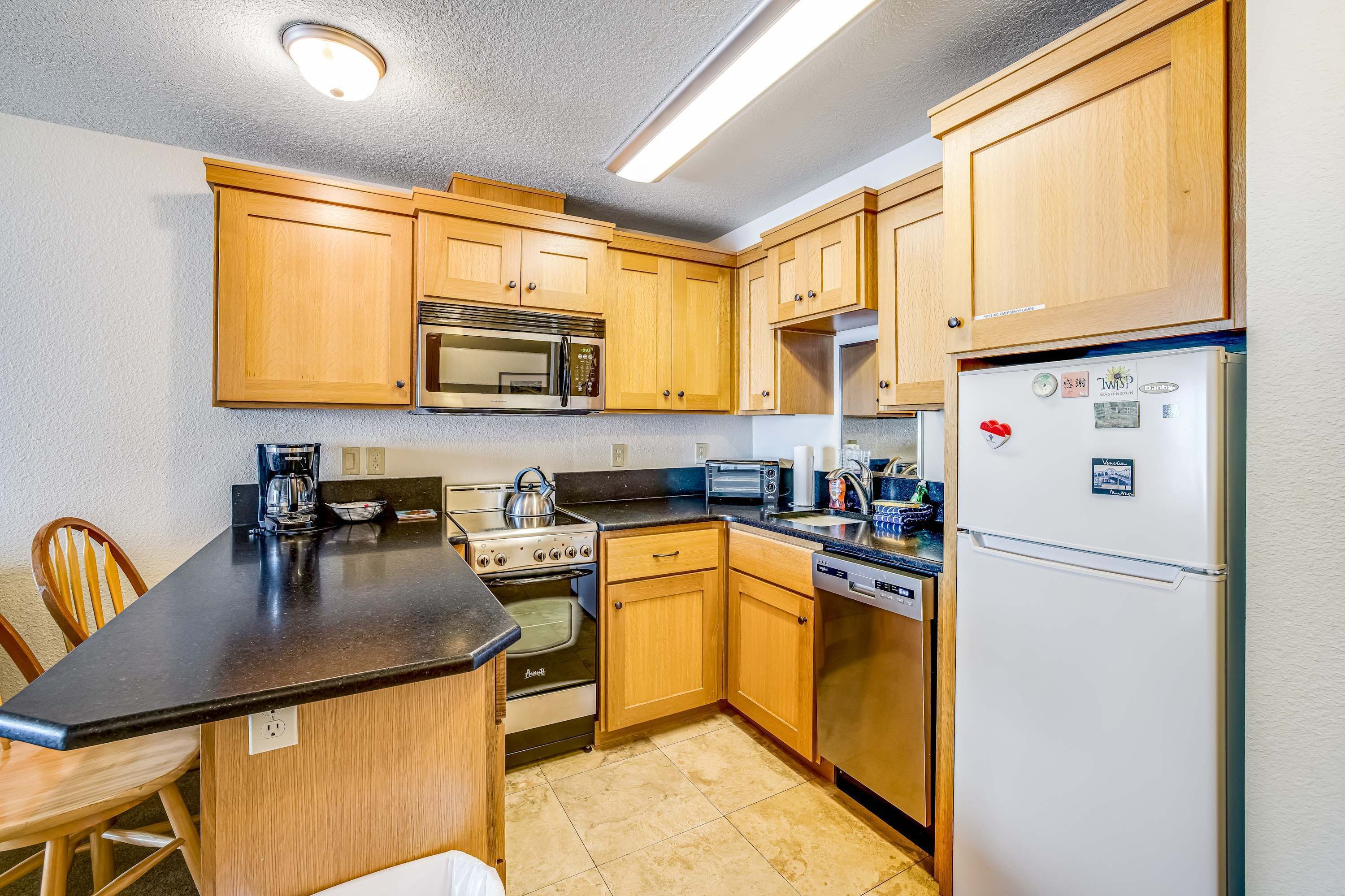 A kitchen with wooden cabinets, a stove, microwave, toaster, and refrigerator.