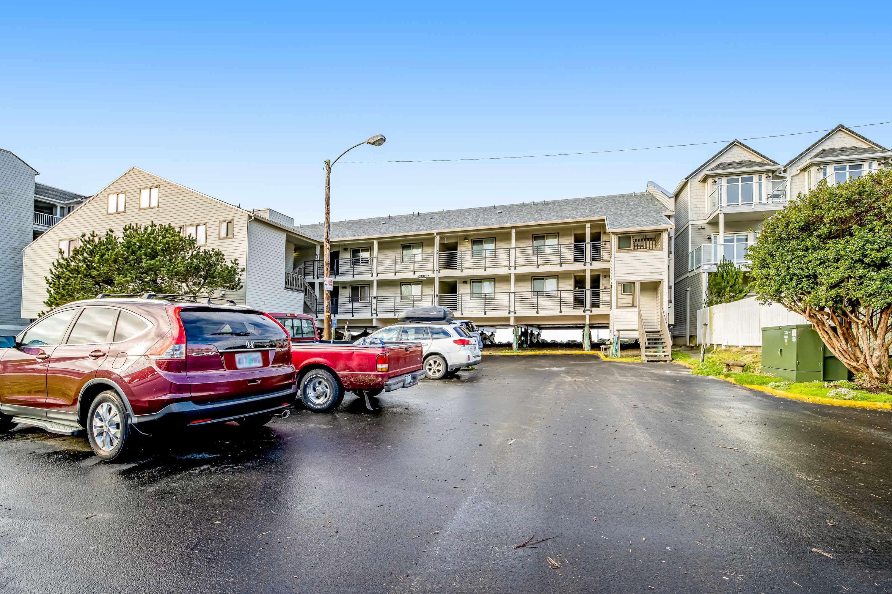 Un immeuble à plusieurs étages avec un parking situé devant.