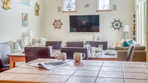 Ein Essbereich mit Tisch, Stühlen und einem Fernseher im Hintergrund.