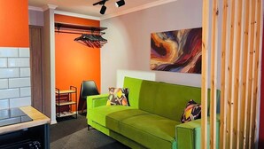 Una sala de estar moderna con un sofá verde, un cuadro en la pared y un separador de madera.