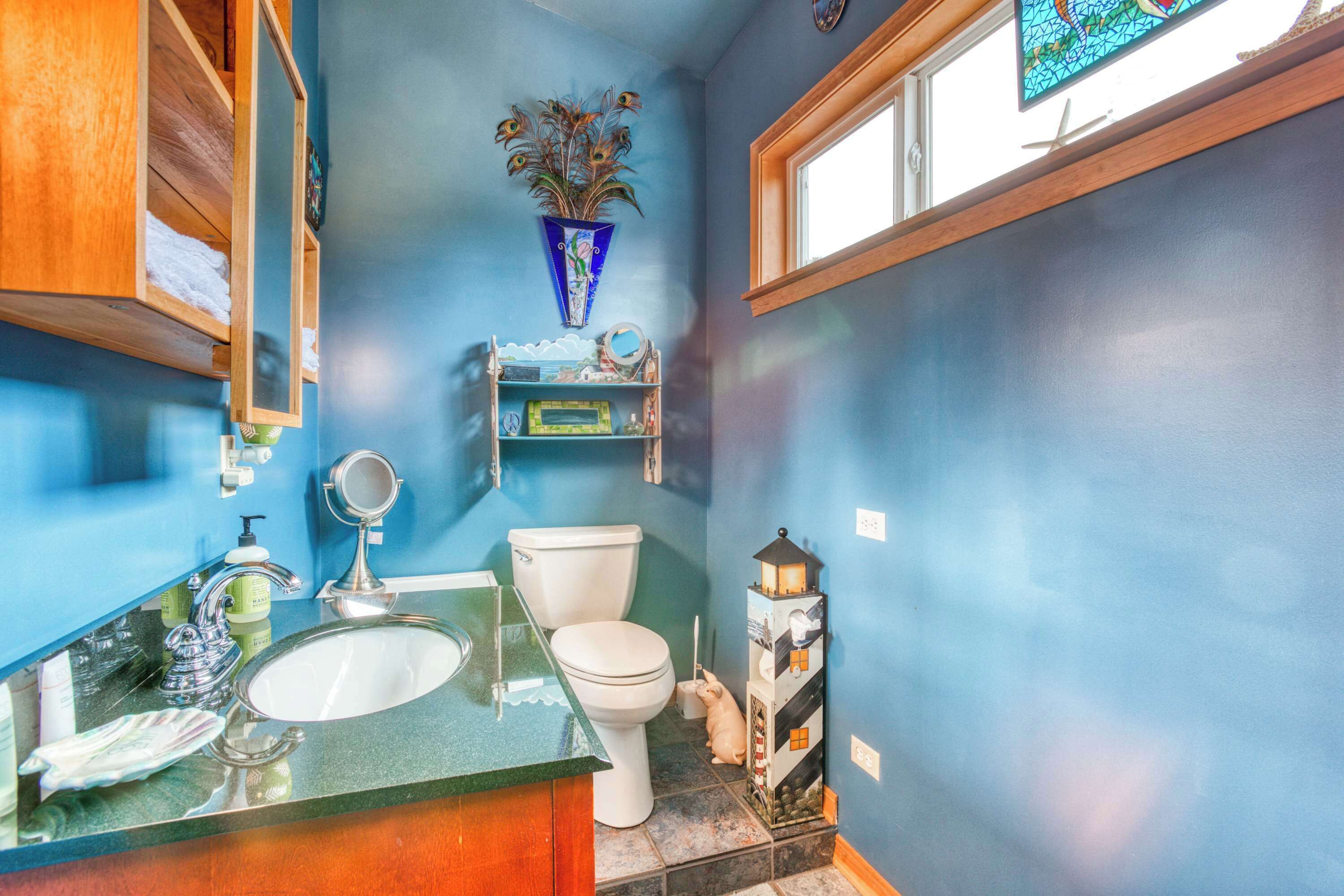 A bathroom with a blue wall, a wooden cabinet, a sink, a toilet, a mirror, and a decorative lantern.