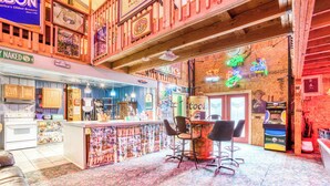 Un'area bar con soffitto in legno, insegne al neon e un bancone con sgabelli.