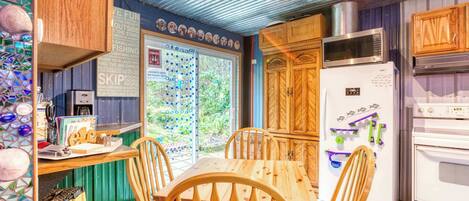 A kitchen with wooden cabinets, a refrigerator, a microwave, and a dining table with chairs.