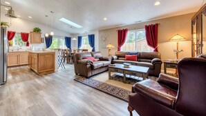 A spacious living area with a kitchen, leather sofas, a coffee table, and a dining area.