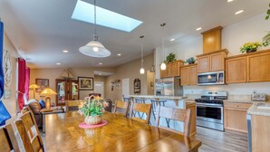 A spacious kitchen with wooden cabinets, a central island, and a dining area with a large wooden table and chairs.