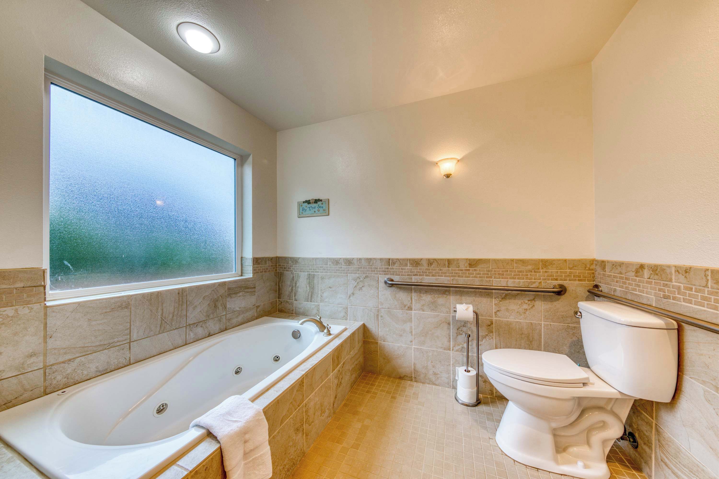 A bathroom with a bathtub, toilet, and a window.