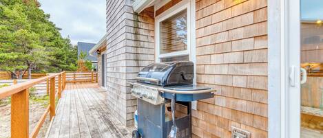 A wooden deck with a barbecue grill and a gas tank.