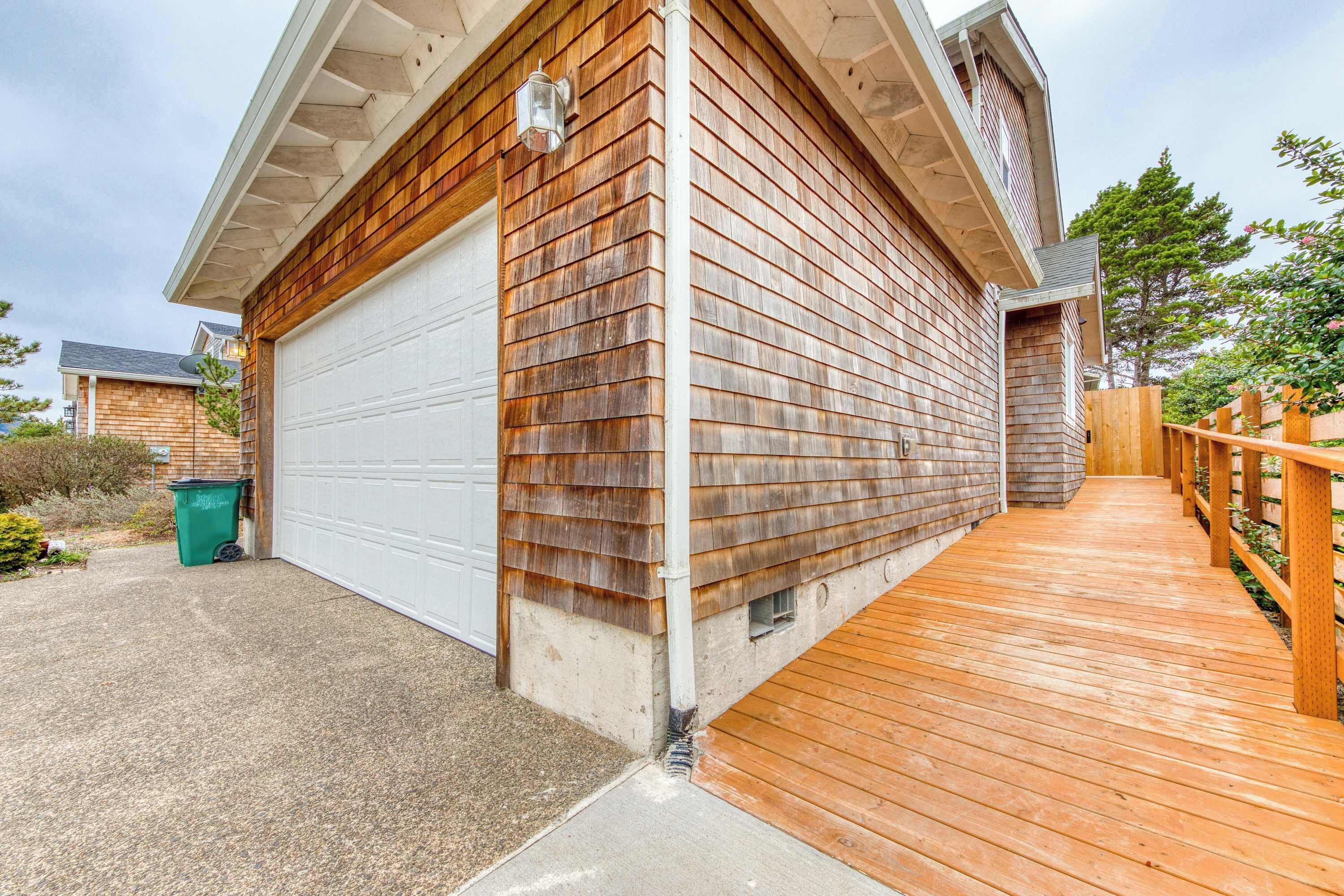 Un immeuble résidentiel avec une façade en bois, une porte de garage blanche et une terrasse en bois donnant sur un porche abrité.