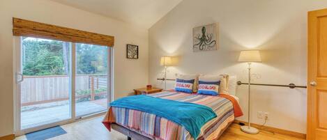 A bedroom with a large bed, two bedside lamps, a sliding glass door to a balcony, and a wooden floor.