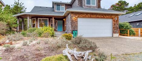 A two-story house with a garage, a covered porch, and a landscaped front yard.