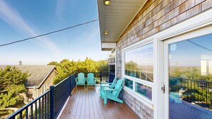Une terrasse en bois avec des sièges d’extérieur et une porte vitrée donnant sur un balcon.