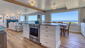 Una cocina amplia con una isla grande, piso de madera y vista al océano.
