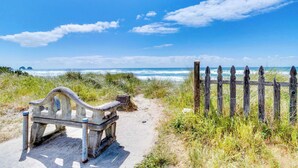 Una panchina e un recinto di legno su una spiaggia sotto un cielo sereno.