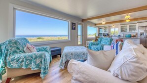 Una habitación acogedora con ventanas amplias, una zona de cocina y vistas a la playa.