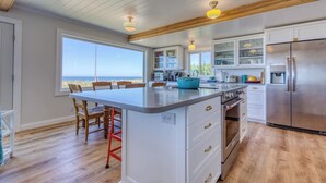 Cocina moderna con una isla central, armarios blancos y un refrigerador grande.